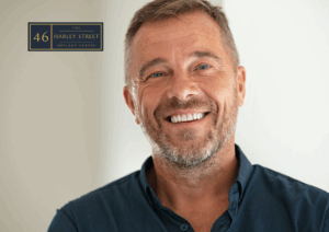 Person smiling while looking into the camera in a blue denim shirt