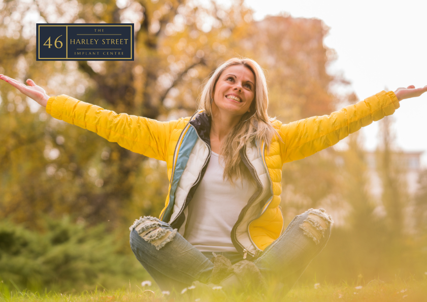 Person sitting happily in grass area whilst smiling.